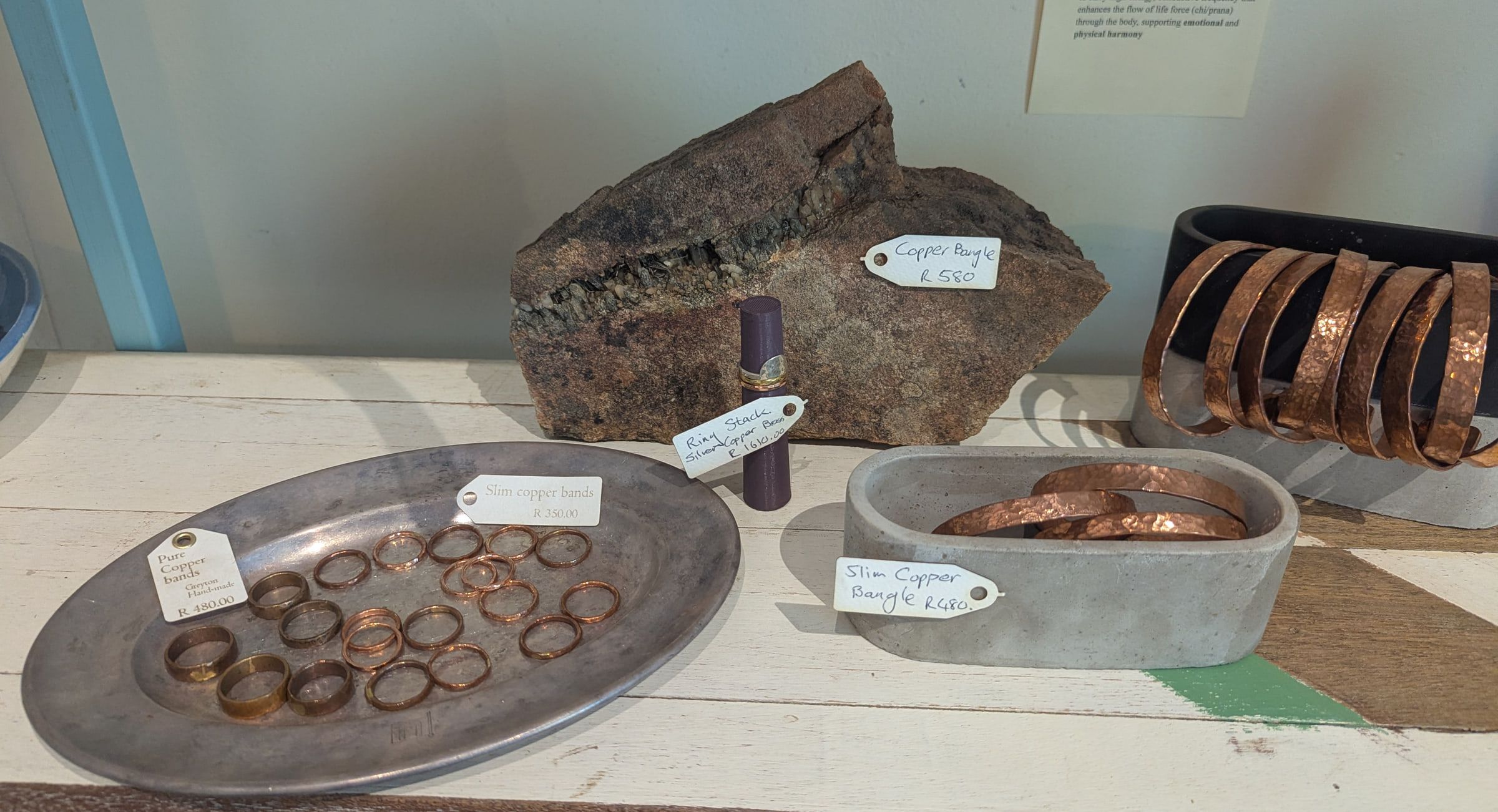 Copper rings and cuffs on a pewter platter and a stone